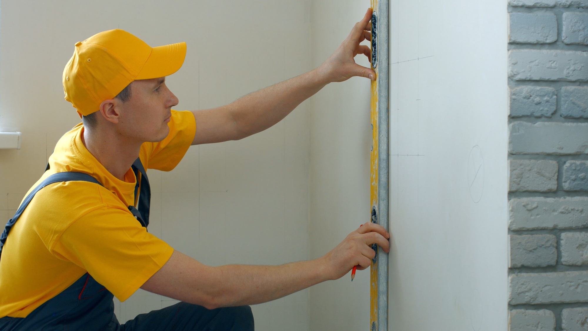 Repairman making measurement of wall.